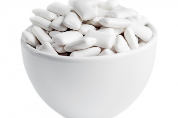 <p>Small white bowl of white rectangular chewing gum isolated on white.</p>